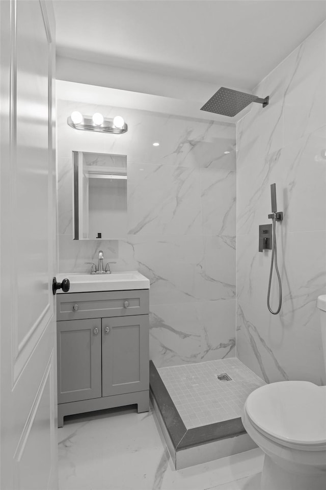 bathroom with vanity, toilet, and tiled shower