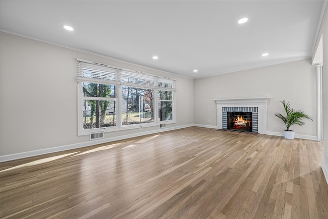 unfurnished living room with ornamental molding, a fireplace, and light wood-type flooring