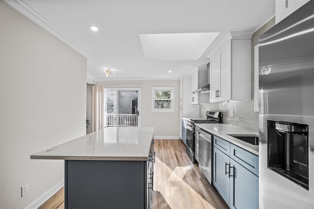 kitchen featuring stainless steel appliances, a center island, light hardwood / wood-style floors, light stone countertops, and decorative backsplash