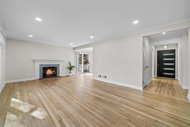 unfurnished living room with ornamental molding, a fireplace, and light hardwood / wood-style flooring