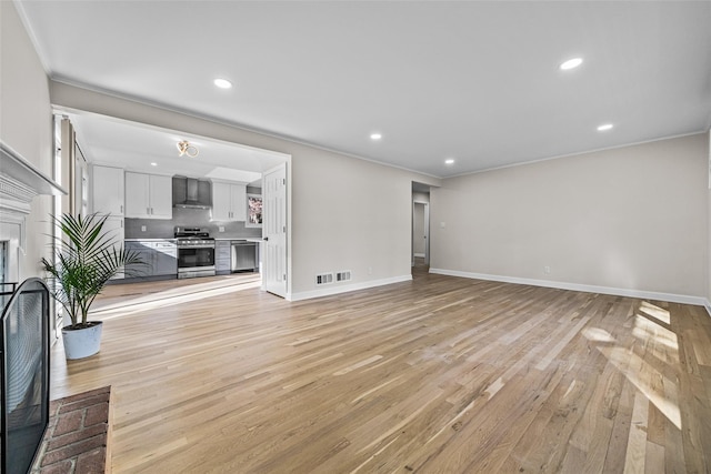 unfurnished living room featuring crown molding and light hardwood / wood-style flooring