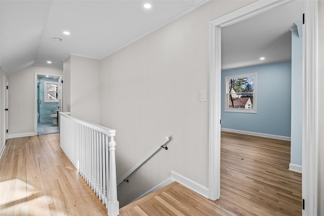 hallway with vaulted ceiling and light wood-type flooring