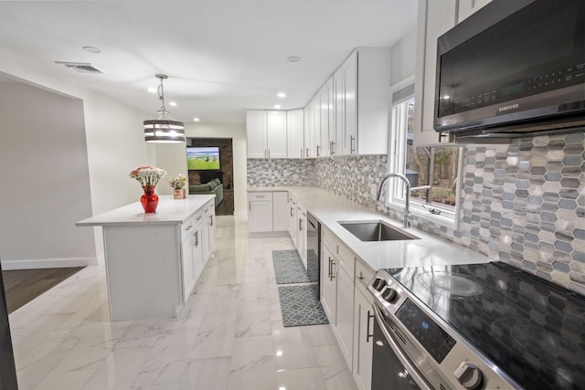 kitchen with sink, white cabinetry, decorative light fixtures, a center island, and appliances with stainless steel finishes