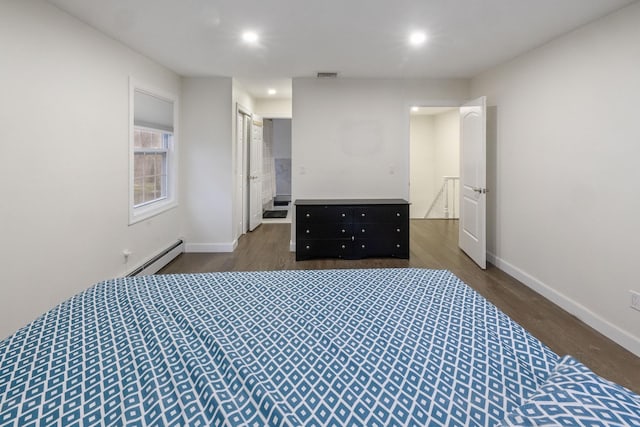 bedroom with dark hardwood / wood-style flooring and a baseboard heating unit