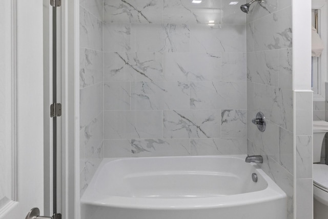 bathroom featuring tiled shower / bath combo and toilet