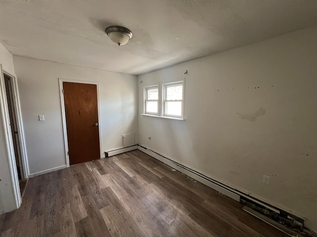 unfurnished bedroom with hardwood / wood-style flooring, a textured ceiling, and baseboard heating