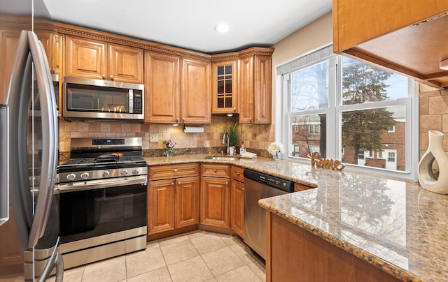 kitchen featuring light tile patterned floors, sink, stainless steel appliances, light stone countertops, and tasteful backsplash