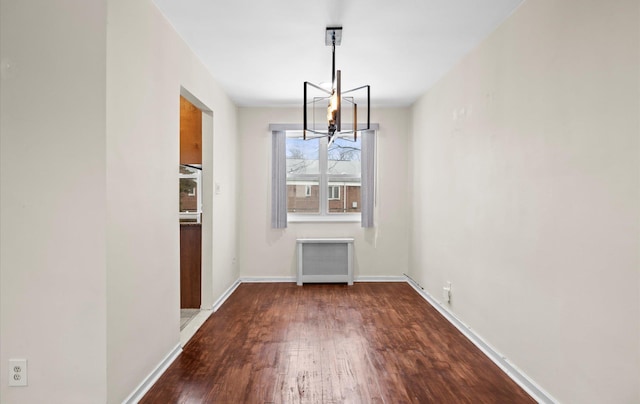 unfurnished dining area featuring an inviting chandelier, wood-type flooring, and radiator heating unit