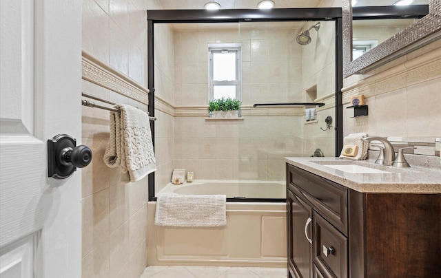 bathroom featuring tile walls, tile patterned flooring, enclosed tub / shower combo, and vanity