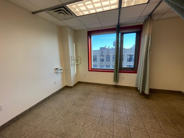 empty room featuring light tile patterned floors and a drop ceiling