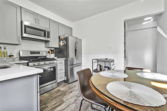 kitchen with backsplash, gray cabinets, and appliances with stainless steel finishes