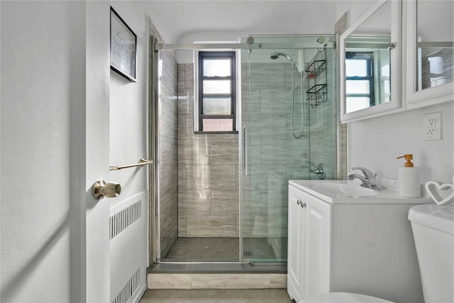 bathroom with a shower with door, vanity, tile patterned flooring, and toilet