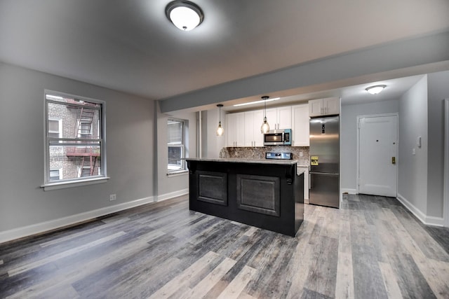 kitchen featuring hanging light fixtures, stainless steel appliances, tasteful backsplash, white cabinets, and a kitchen island