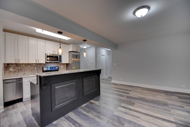 kitchen featuring light hardwood / wood-style flooring, white cabinetry, backsplash, stainless steel appliances, and decorative light fixtures