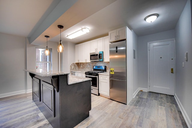 kitchen featuring light stone counters, tasteful backsplash, hanging light fixtures, appliances with stainless steel finishes, and white cabinets