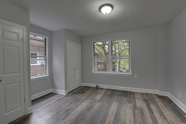 spare room with dark wood-type flooring and a healthy amount of sunlight