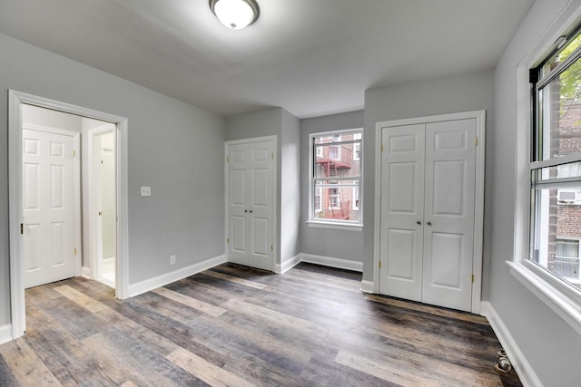 unfurnished bedroom with multiple windows and dark wood-type flooring