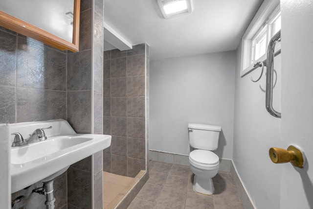 bathroom featuring a shower, sink, tile walls, tile patterned flooring, and toilet