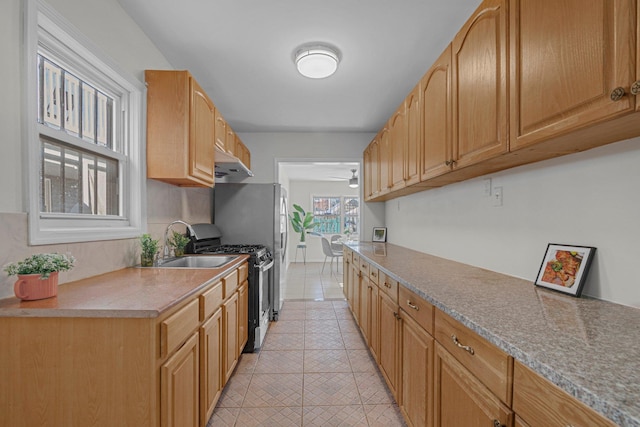 kitchen featuring stainless steel gas range oven, sink, and ceiling fan