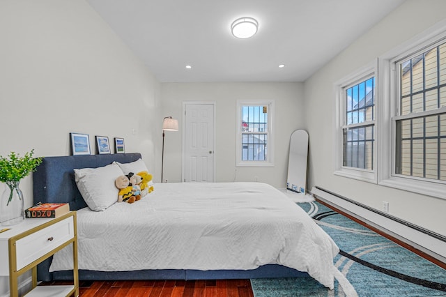 bedroom with a baseboard heating unit and dark wood-type flooring