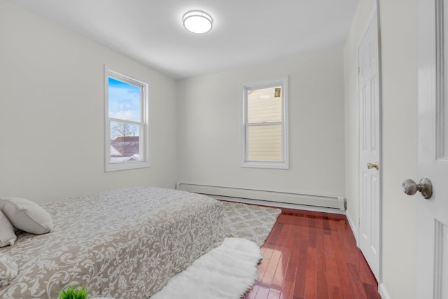 bedroom featuring a baseboard heating unit and dark hardwood / wood-style floors