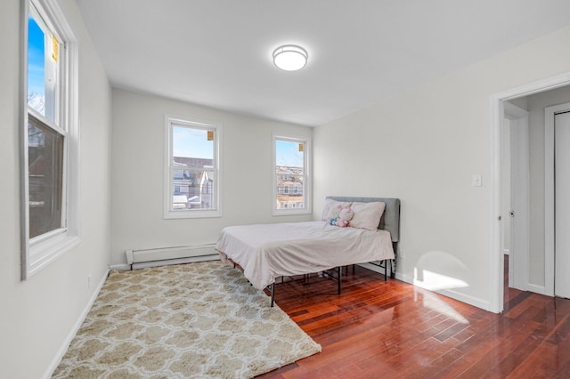 bedroom with hardwood / wood-style floors and a baseboard heating unit