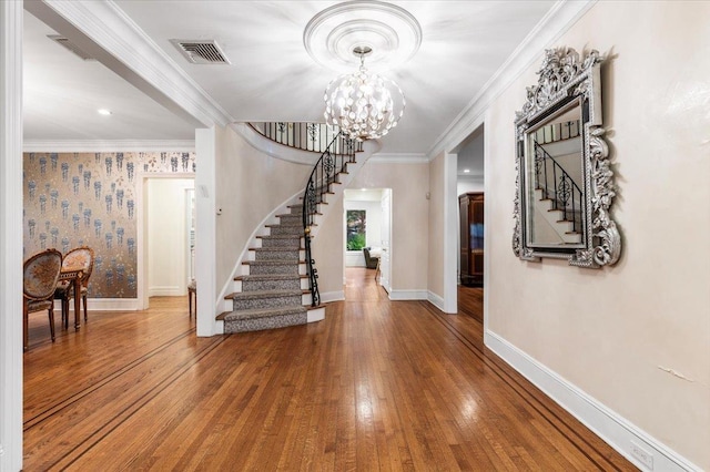 foyer entrance featuring an inviting chandelier, hardwood / wood-style flooring, and ornamental molding