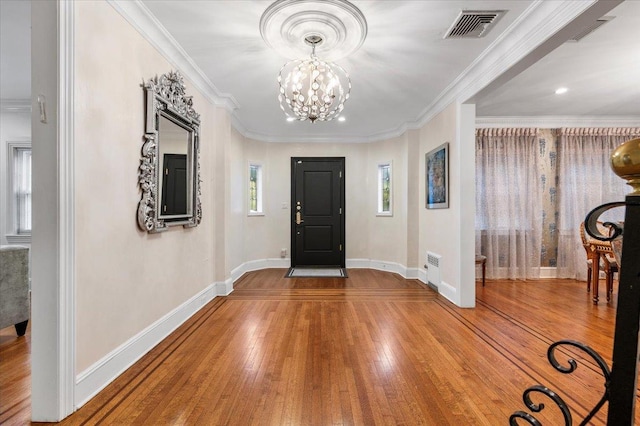 entrance foyer featuring an inviting chandelier, hardwood / wood-style floors, and crown molding