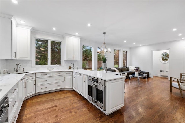 kitchen featuring white cabinetry, wood-type flooring, sink, and radiator heating unit