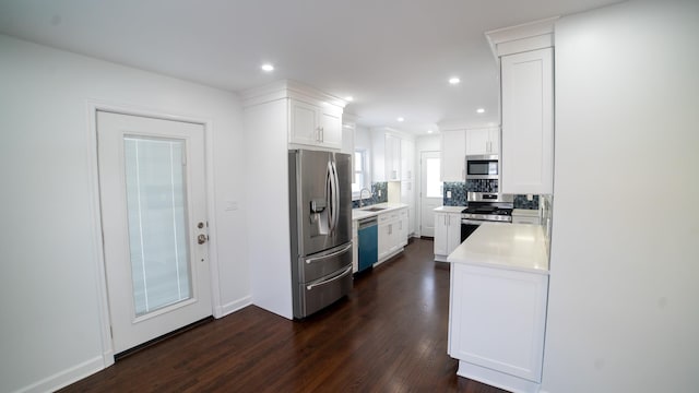 kitchen with appliances with stainless steel finishes, dark hardwood / wood-style floors, white cabinetry, sink, and decorative backsplash