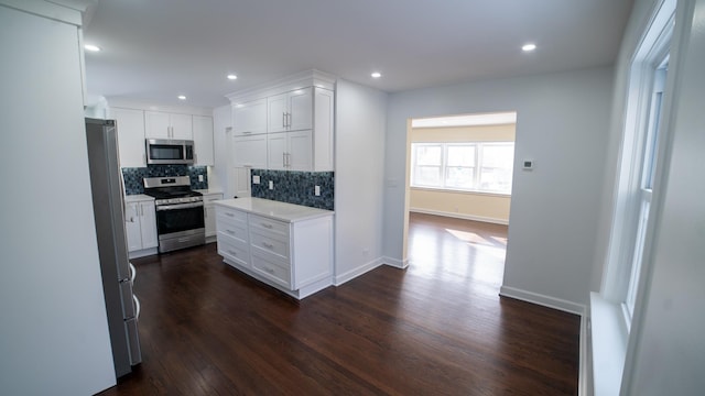 kitchen with white cabinetry, backsplash, dark hardwood / wood-style flooring, and appliances with stainless steel finishes