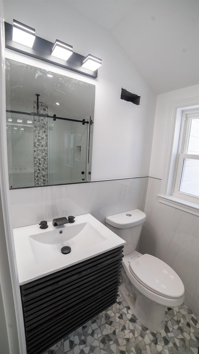 bathroom featuring toilet, a shower with door, vaulted ceiling, and tile walls