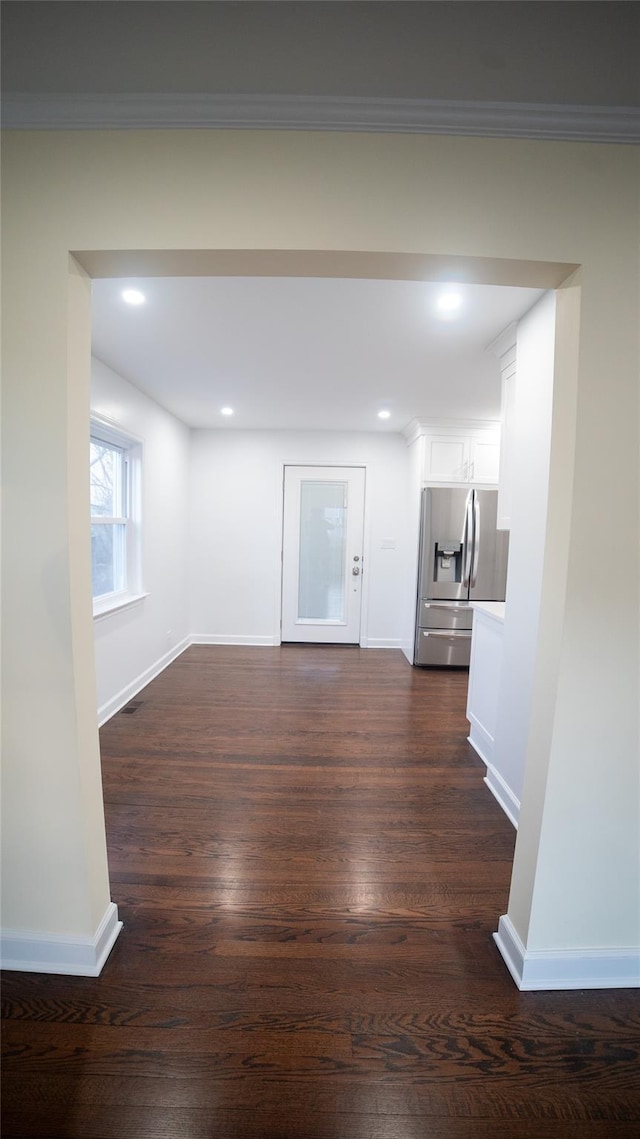 unfurnished living room featuring crown molding and dark hardwood / wood-style floors