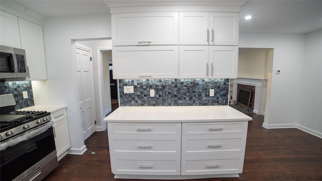 kitchen with stainless steel appliances, white cabinetry, and dark hardwood / wood-style floors