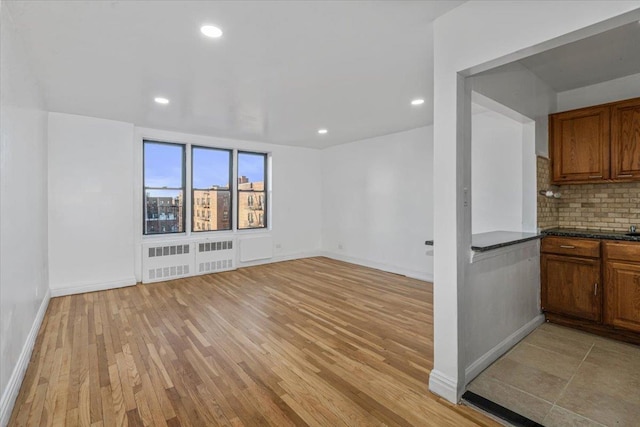 unfurnished living room featuring radiator heating unit and light hardwood / wood-style flooring