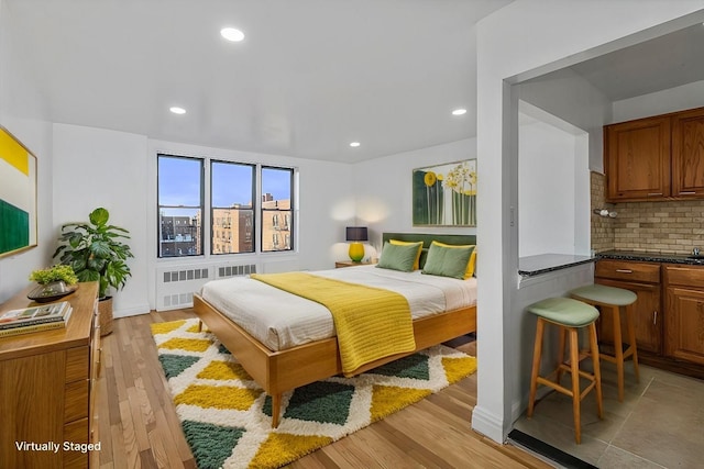 bedroom with radiator heating unit and light hardwood / wood-style flooring