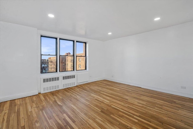 unfurnished room with recessed lighting, radiator heating unit, and hardwood / wood-style flooring