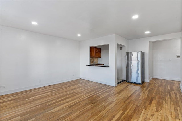 unfurnished living room featuring recessed lighting, light wood-style flooring, and baseboards