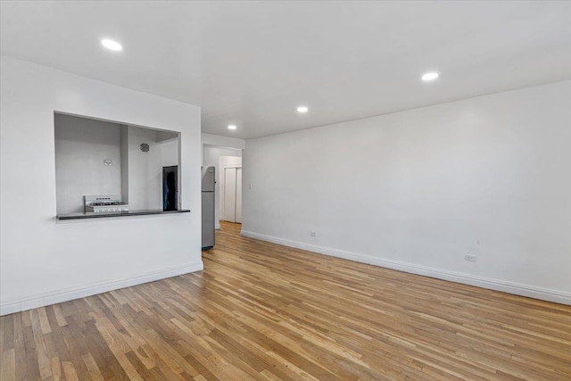 unfurnished living room featuring baseboards, light wood-style flooring, and recessed lighting