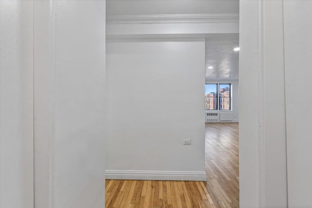 hallway featuring radiator, light wood-style flooring, and baseboards