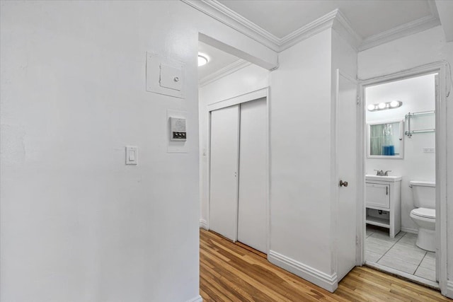 hall with ornamental molding and wood finished floors