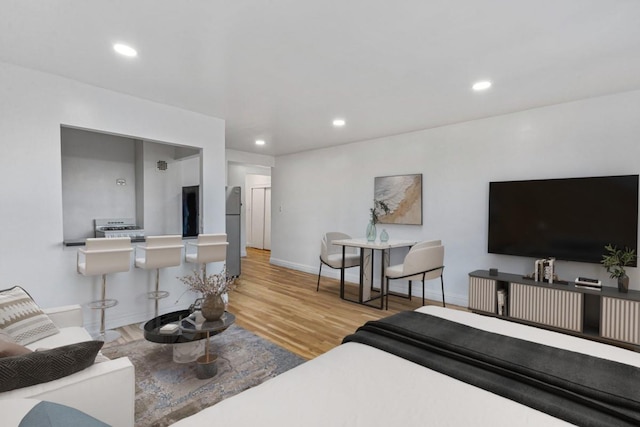 bedroom featuring freestanding refrigerator, baseboards, wood finished floors, and recessed lighting