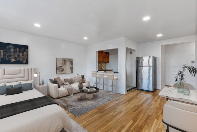 bedroom with light wood finished floors, recessed lighting, baseboards, and freestanding refrigerator