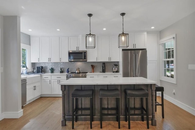 kitchen featuring high end appliances, pendant lighting, a center island, and white cabinets