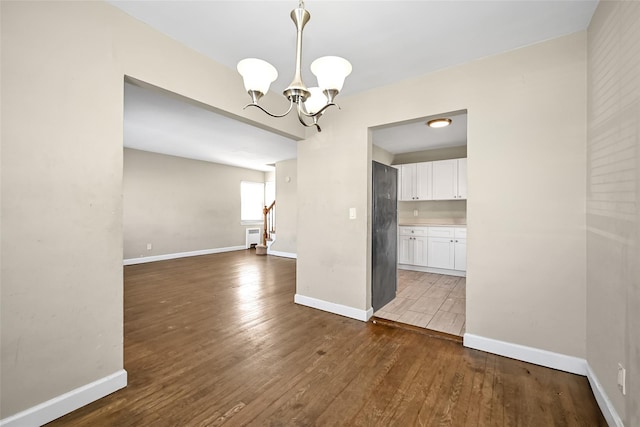 unfurnished dining area with a notable chandelier and dark hardwood / wood-style floors