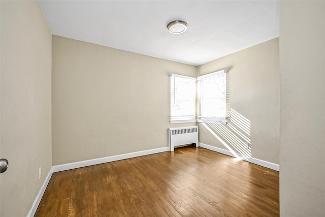 empty room with hardwood / wood-style flooring and radiator