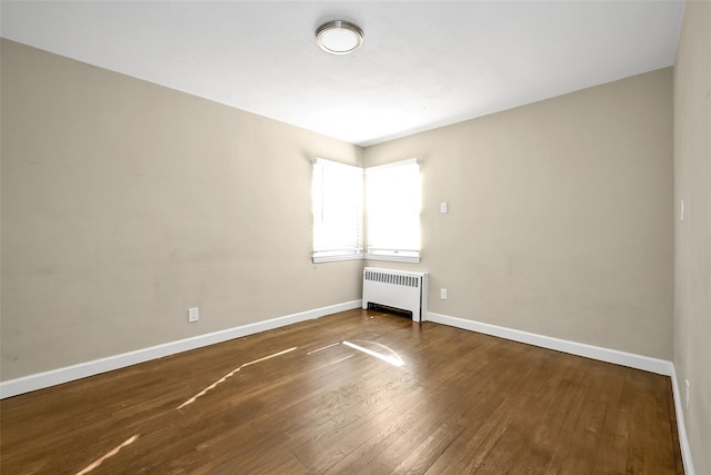 empty room with radiator heating unit and hardwood / wood-style floors