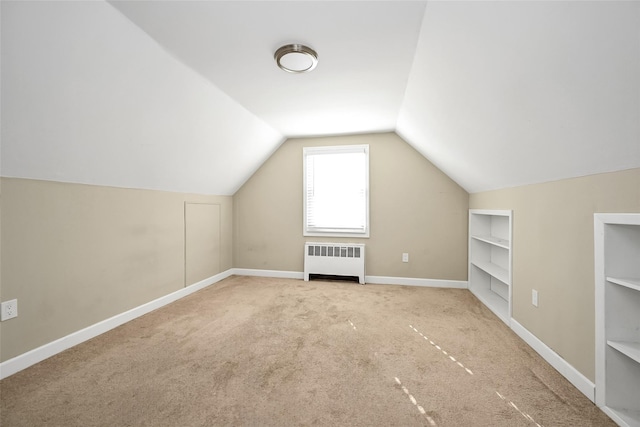 bonus room featuring lofted ceiling, radiator heating unit, light carpet, and built in features