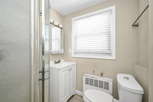 bathroom featuring vanity, radiator, a shower, and toilet