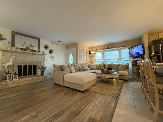 living room featuring wood-type flooring and a brick fireplace